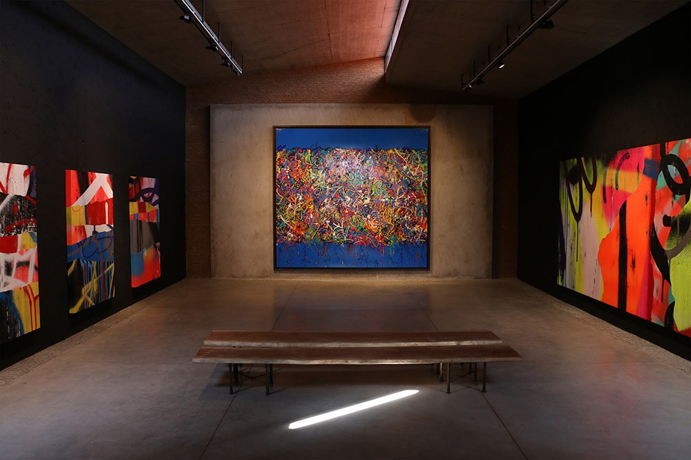 an art space with huge paintings and a bench